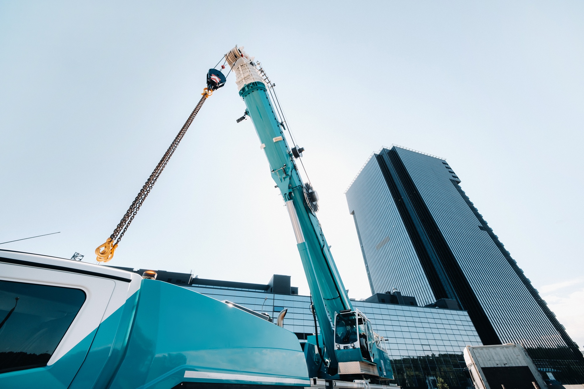 blue crane lifting mechanism with hooks near the glass modern building, crane and hydraulic high