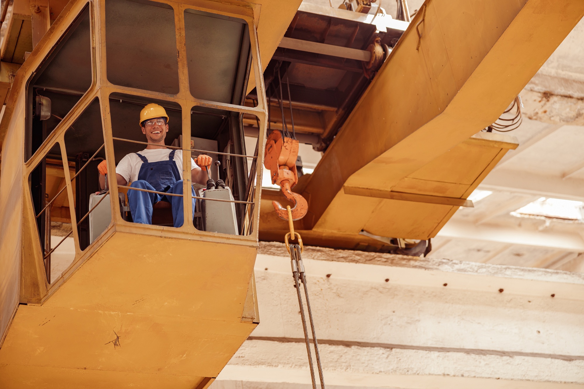 Cheerful man sitting in operator cabin of overhead crane