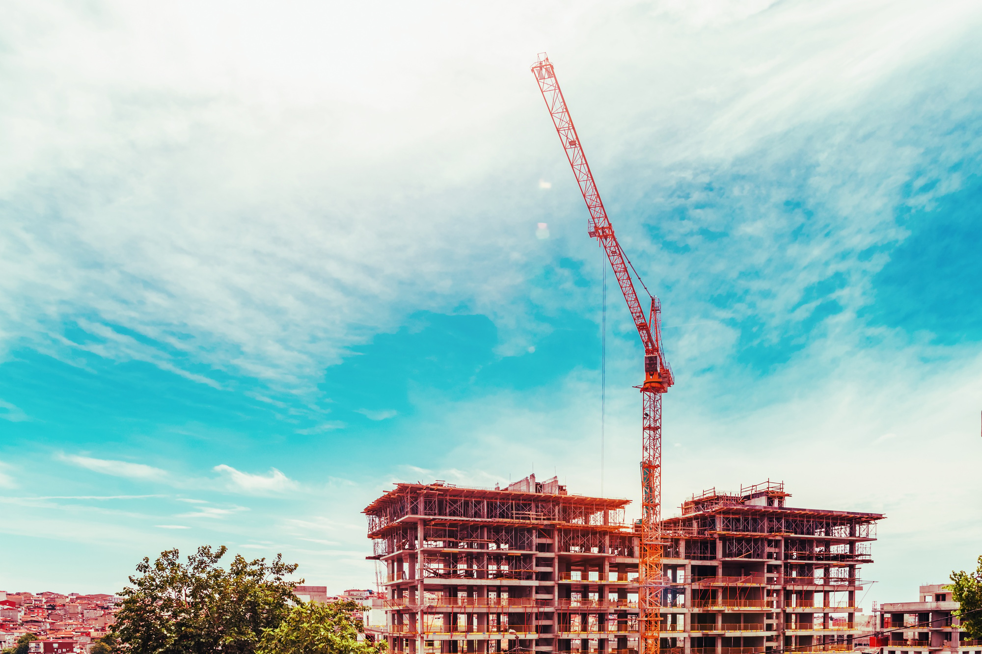 High crane and building under construction against cloudy sky