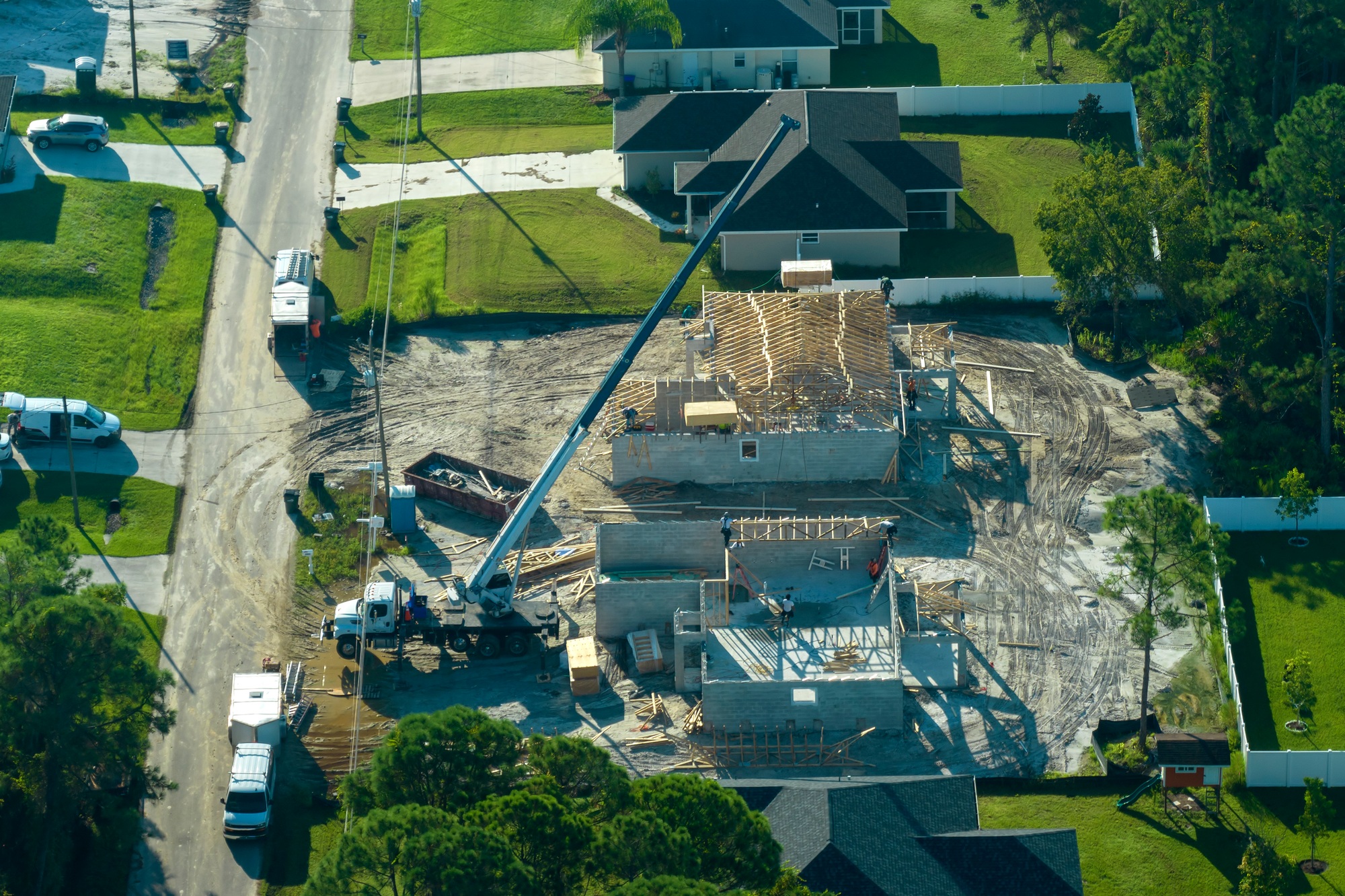 Lifting crane truck and builders working on roof construction