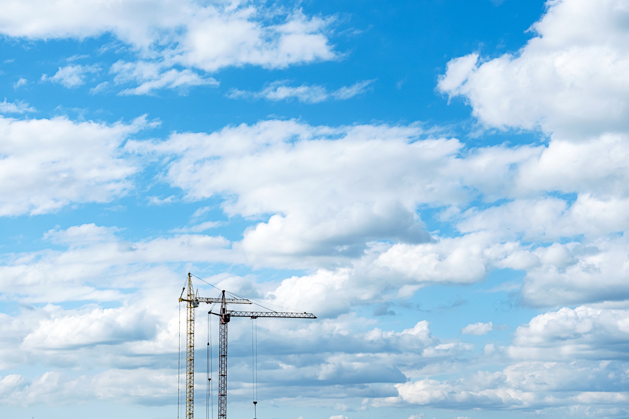 Two Construction Cranes Against the Sky. Tower Crane for Lifting Loads, Construction of Buildings.