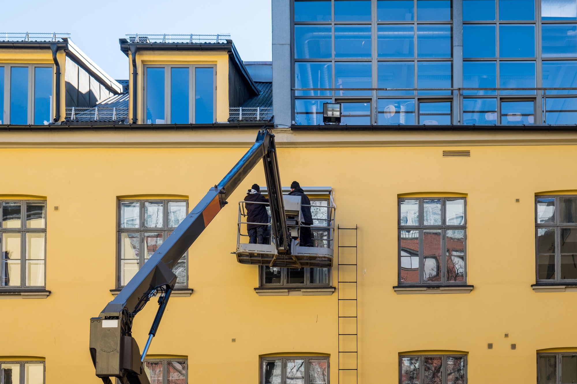 Two mechanic man on hydraulic crane with repairing window