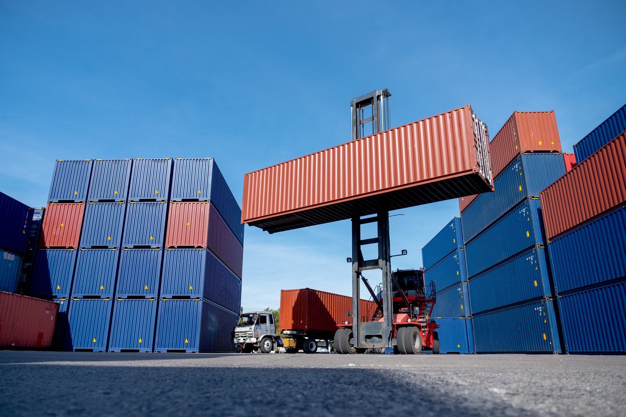 Wide shot of crane truck level up cargo container tank also show stack or layer of containers